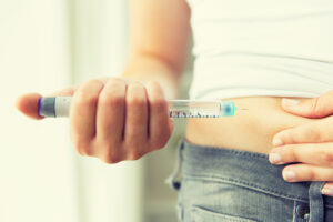 Image of woman injecting medication from a prefilled syringe into her stomach